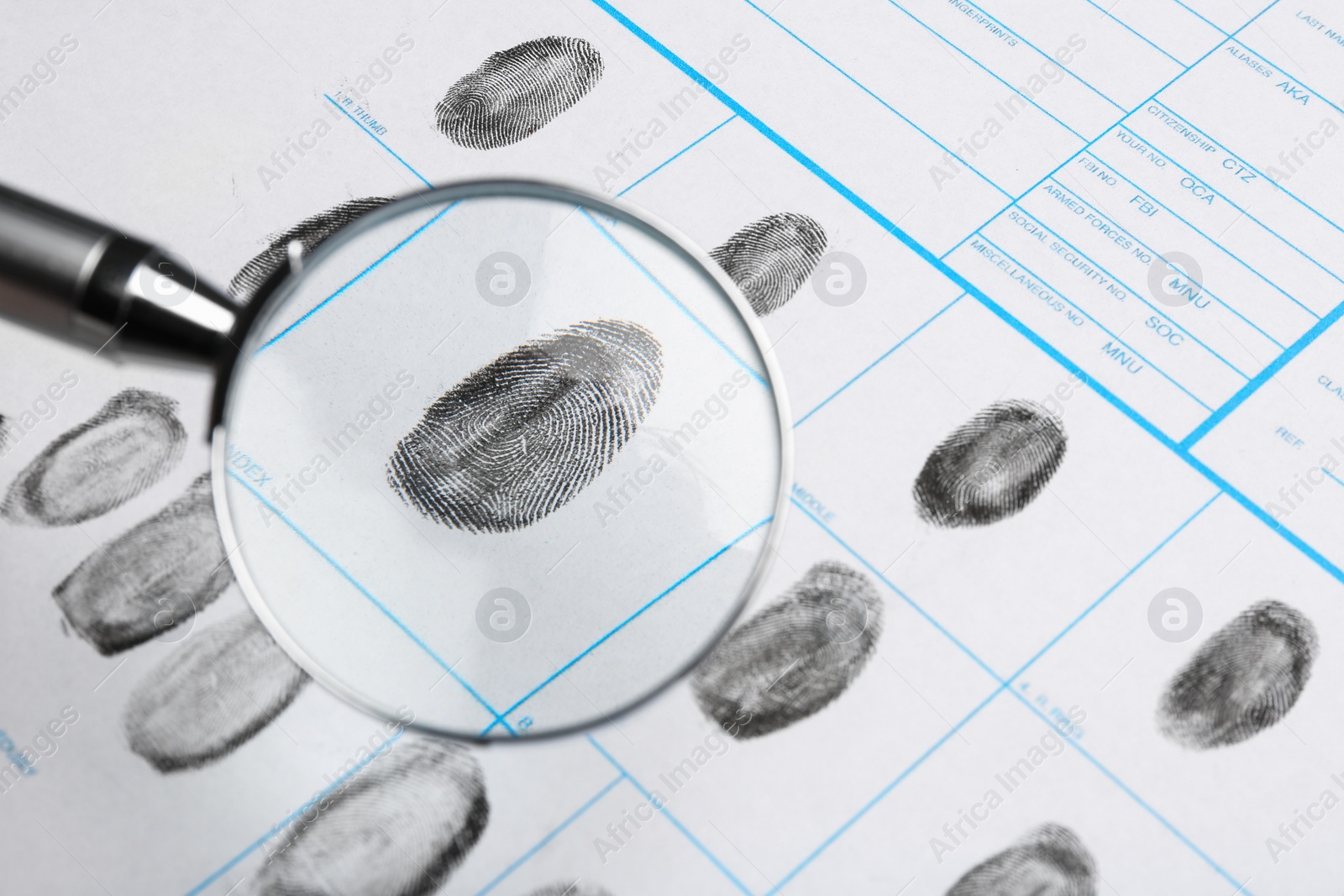 Photo of Magnifying glass and criminal fingerprint card, closeup