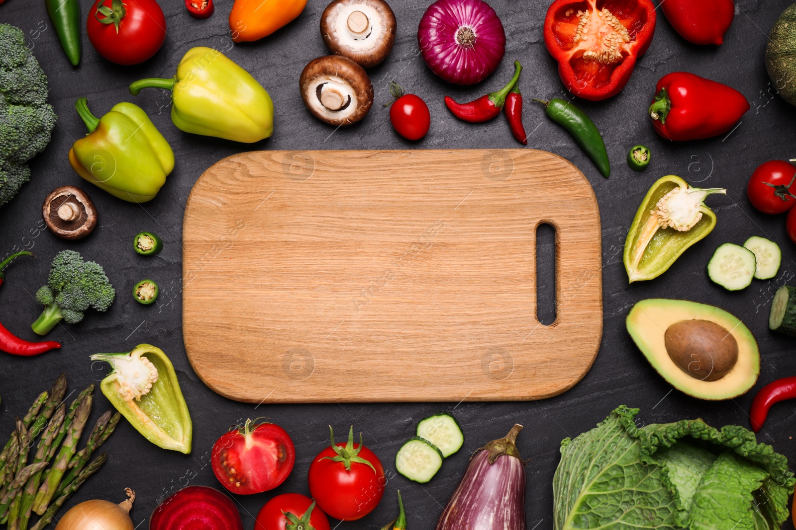 Photo of Wooden board and fresh vegetables on black table, flat lay. Space for text