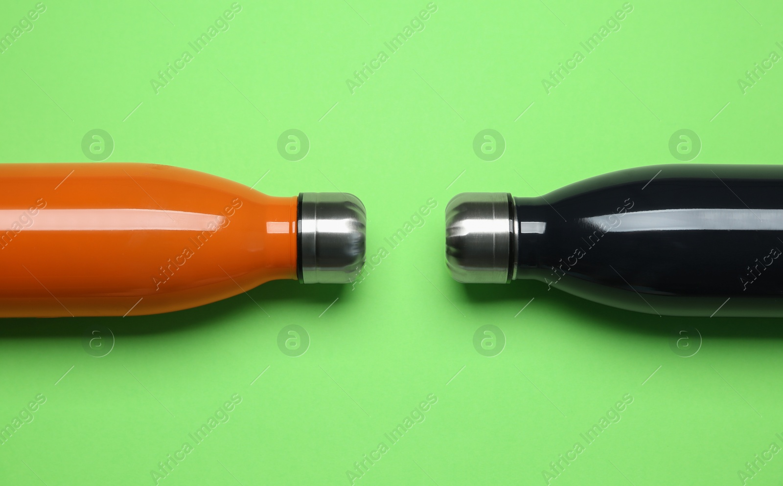 Photo of Different thermo bottles on green background, flat lay