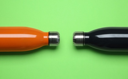 Different thermo bottles on green background, flat lay