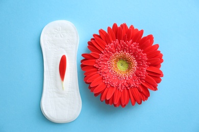 Flat lay composition with red flower and menstrual pad on color background. Gynecological care