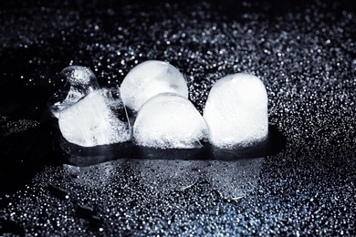 Photo of Melting ice cubes and water drops on black background. Frozen liquid