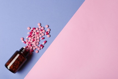 Photo of Bottle with vitamin pills and capsules on color background, flat lay. Space for text