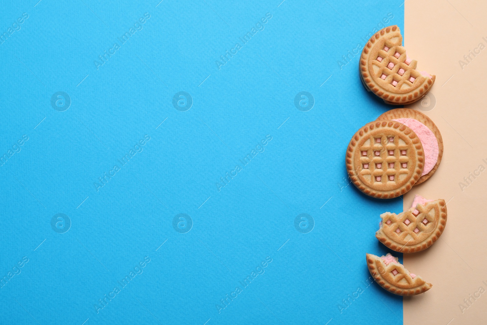 Photo of Tasty sandwich cookies with cream on color background, flat lay. Space for text