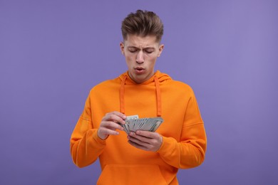 Handsome man with money on purple background