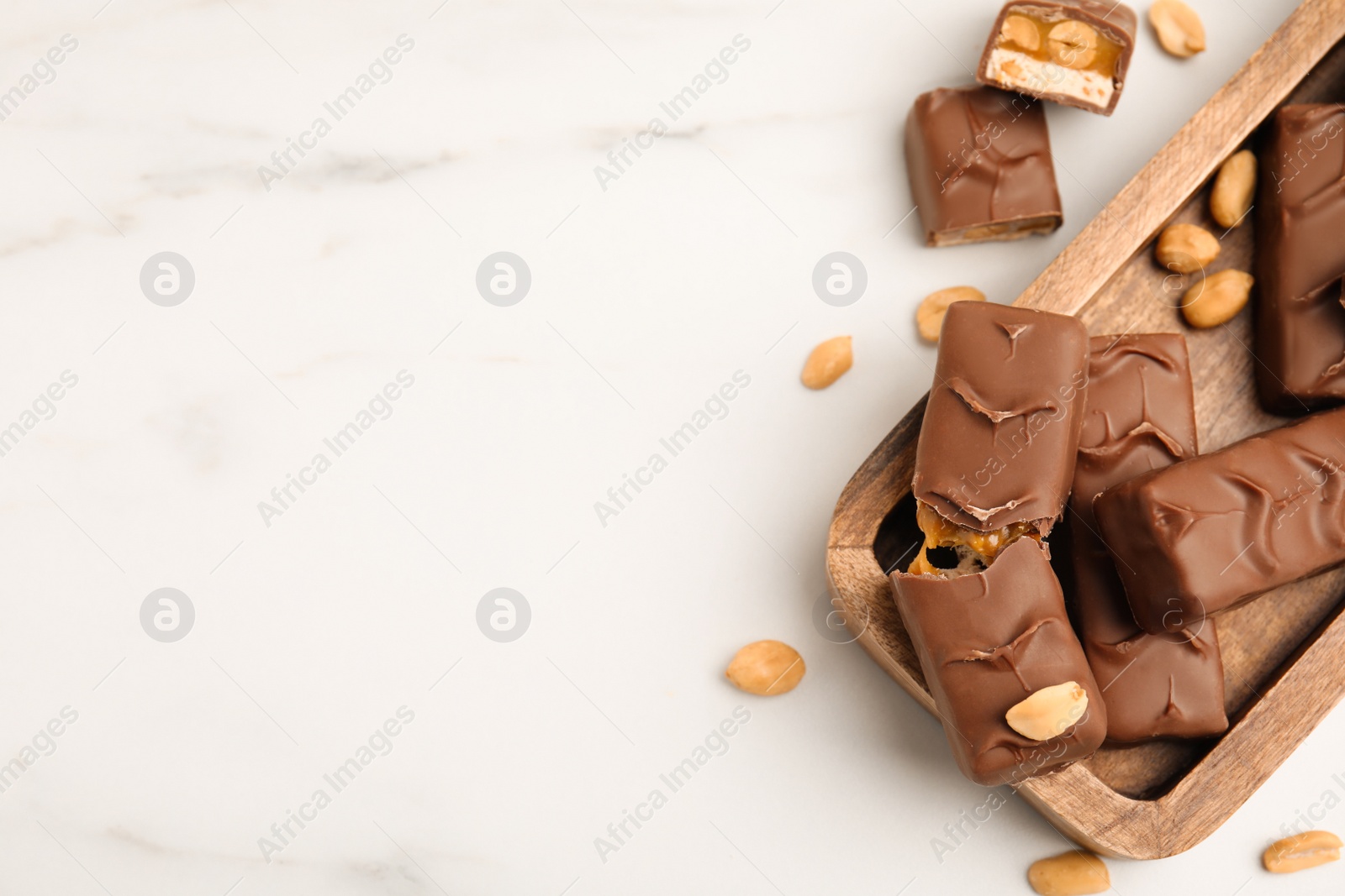 Photo of Chocolate bars with caramel, nuts and nougat on white marble table, flat lay. Space for text