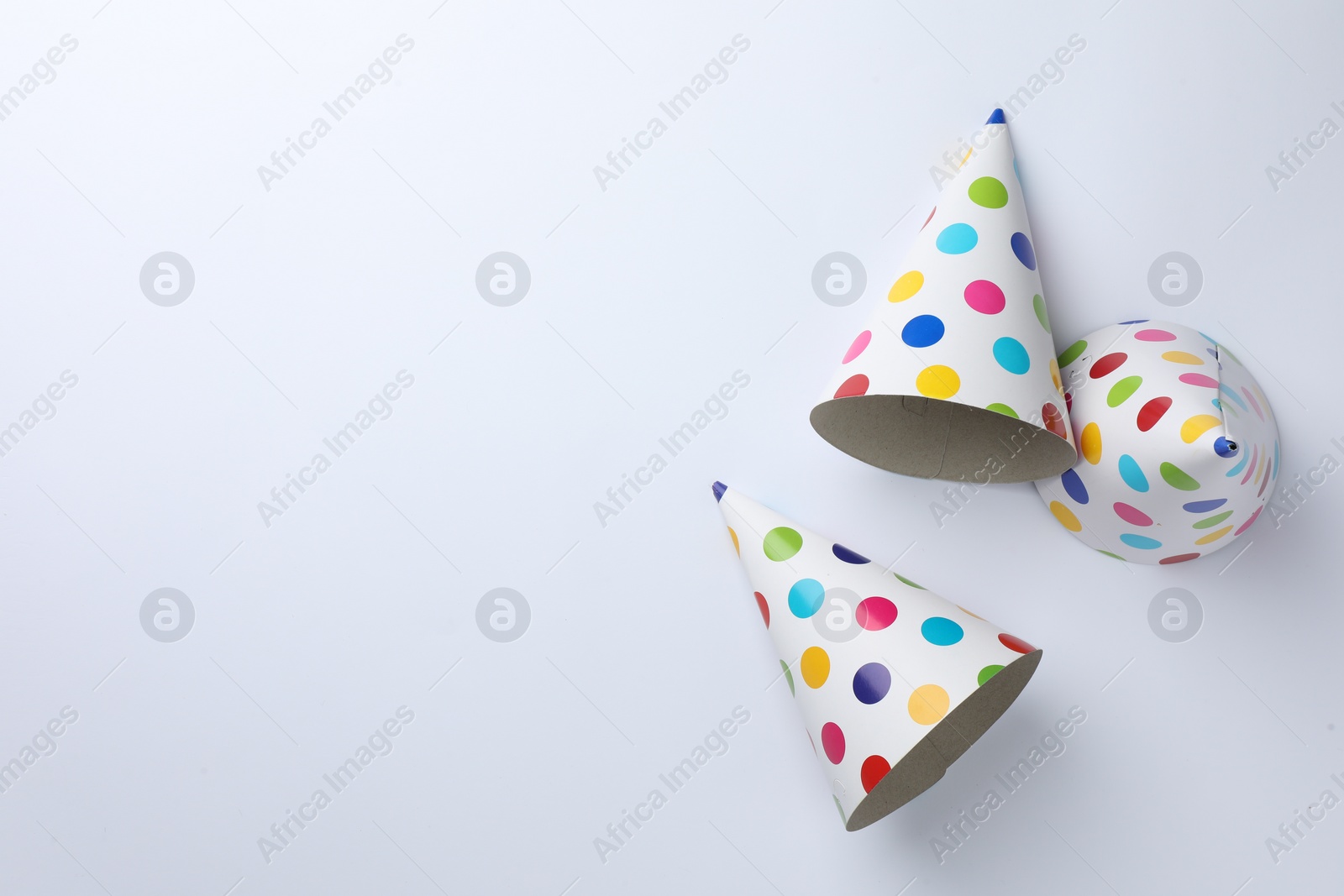 Photo of Colorful party hats on light background, top view. Space for text