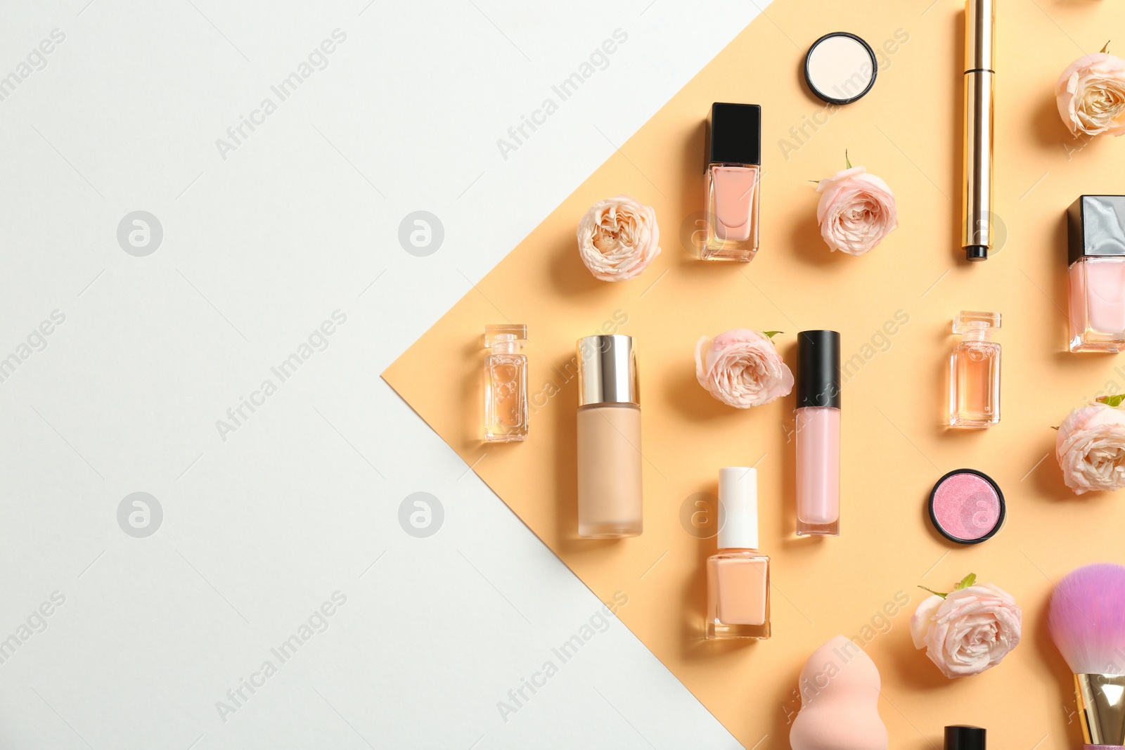 Photo of Flat lay composition with bottles of perfume, cosmetics and roses on color background. Space for text