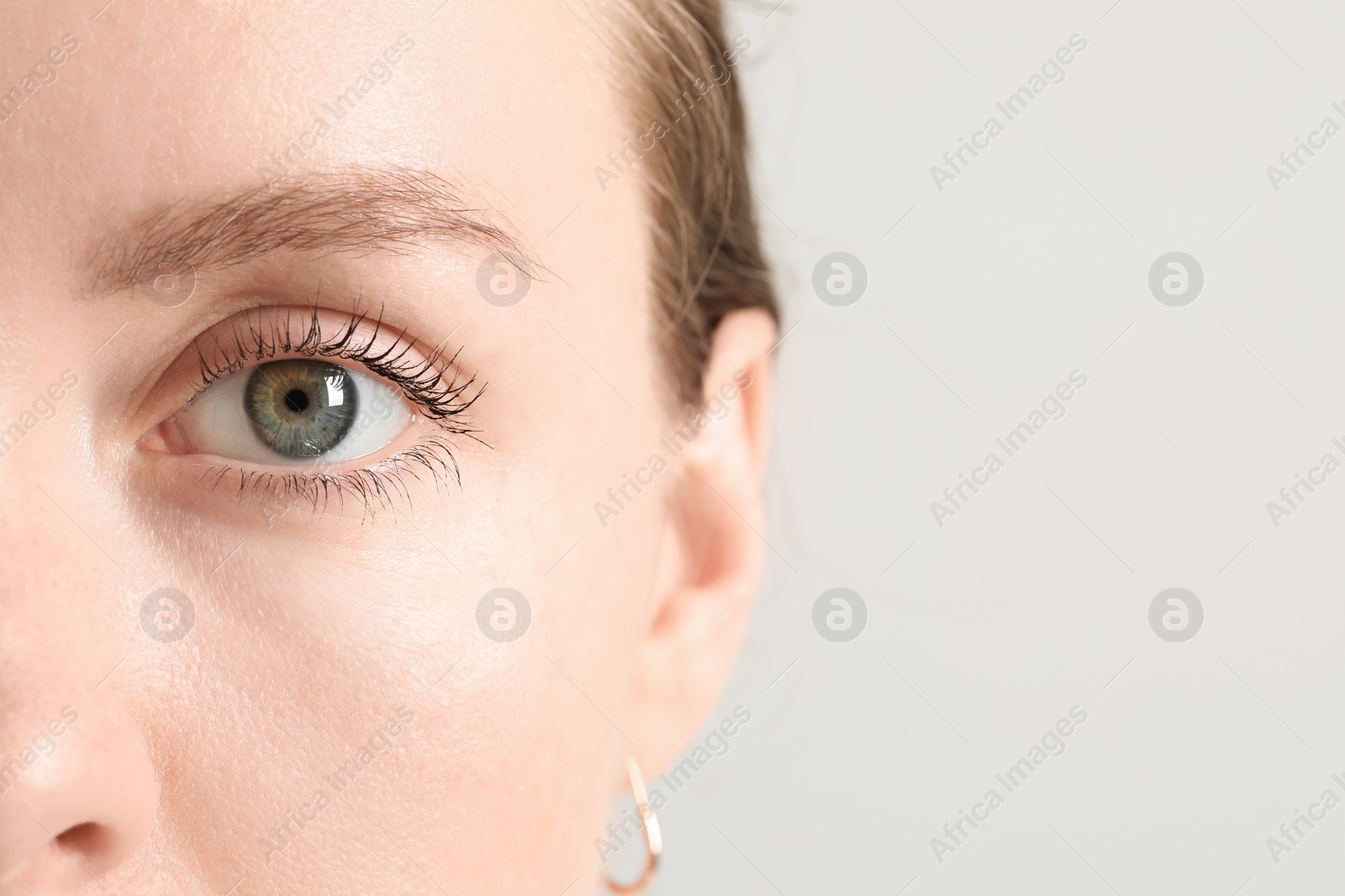 Photo of Closeup photo of woman with beautiful eyes on light background. Space for text