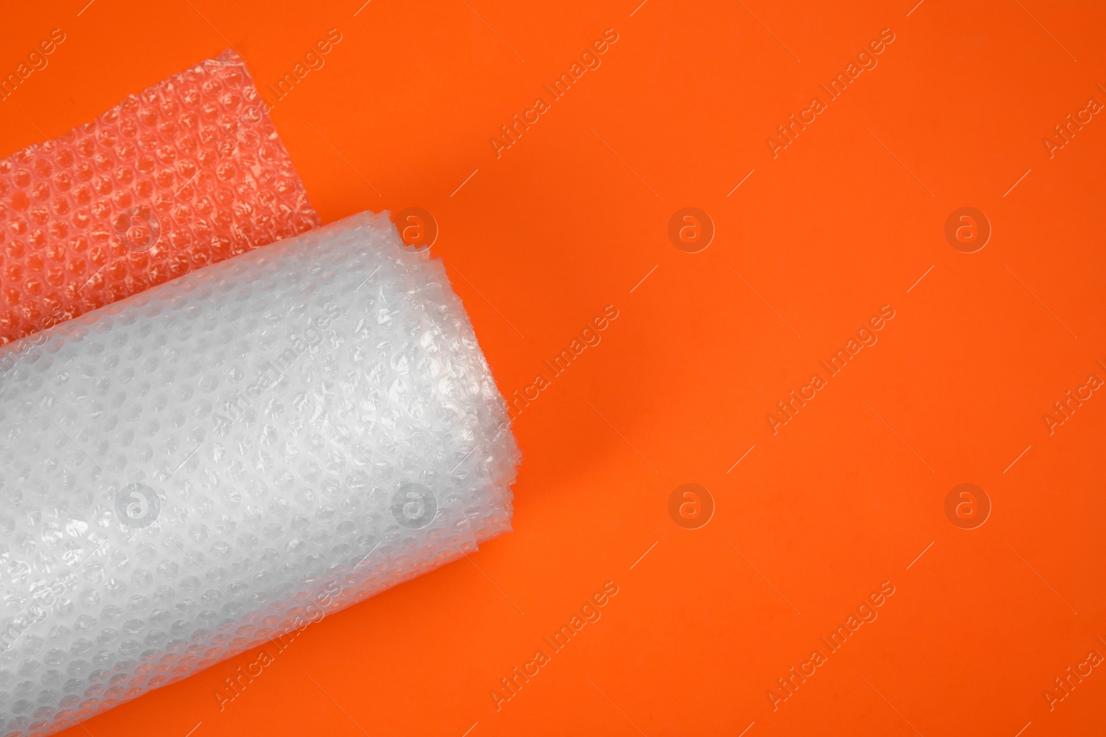 Photo of Bubble wrap roll on orange background, top view. Space for text