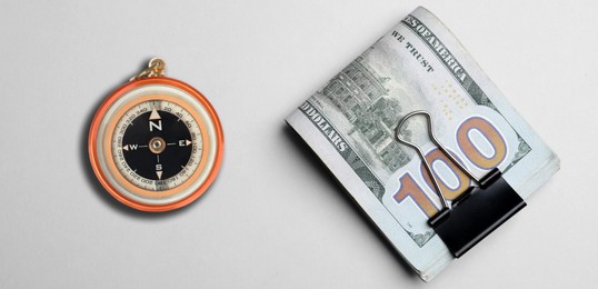 Image of Exchange rate. Money (dollar banknotes) and compass on white background, flat lay. Banner design
