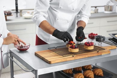 Pastry chefs preparing desserts at table in kitchen, closeup