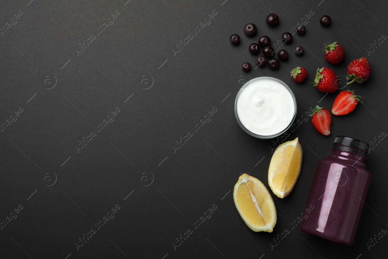 Photo of Bottle of acai drink and ingredients on black background, flat lay. Space for text