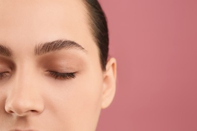 Photo of Young woman with perfect eyebrows on pink background, closeup. Space for text
