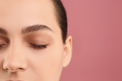 Young woman with perfect eyebrows on pink background, closeup. Space for text