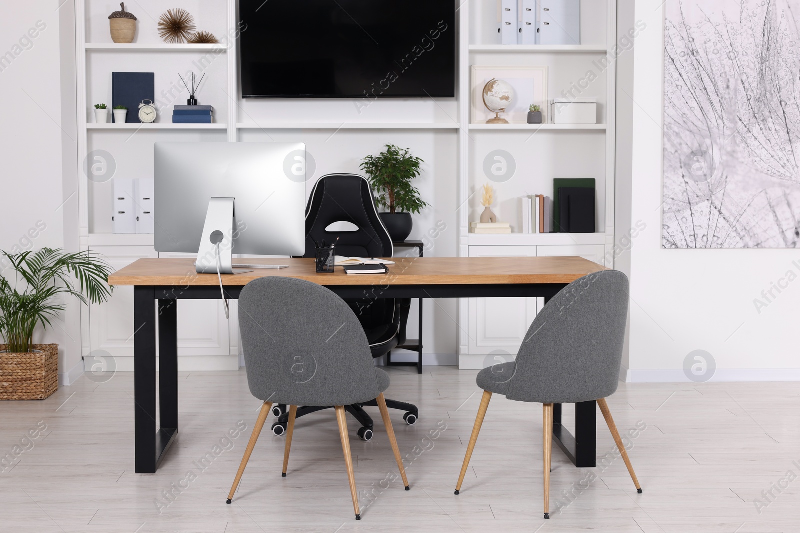 Photo of Stylish director's workplace with wooden table, tv zone, shelves and comfortable armchairs in room. Interior design