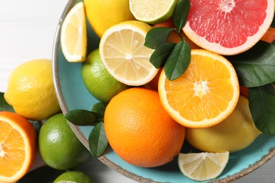 Different cut and whole citrus fruits on white table, top view