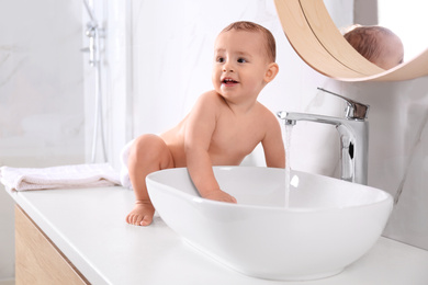 Photo of Cute little baby playing in bathroom at home