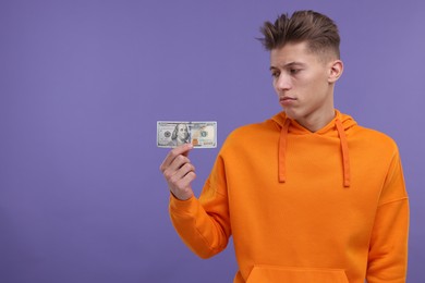 Photo of Upset man with dollar banknote on purple background. Space for text