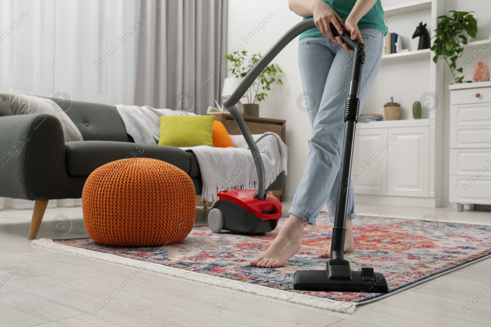 Photo of Woman cleaning carpet with vacuum cleaner at home, closeup