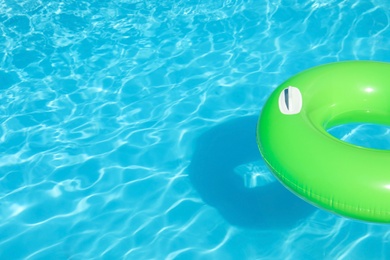 Inflatable ring floating in swimming pool on sunny day. Space for text