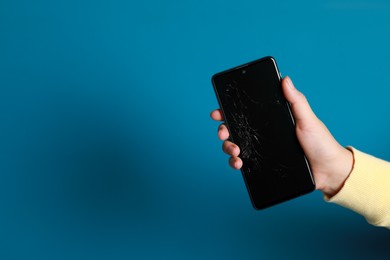 Woman holding damaged smartphone on light blue background, closeup with space for text. Device repairing