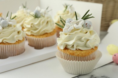 Photo of Tasty Easter cupcakes with vanilla cream on table, closeup