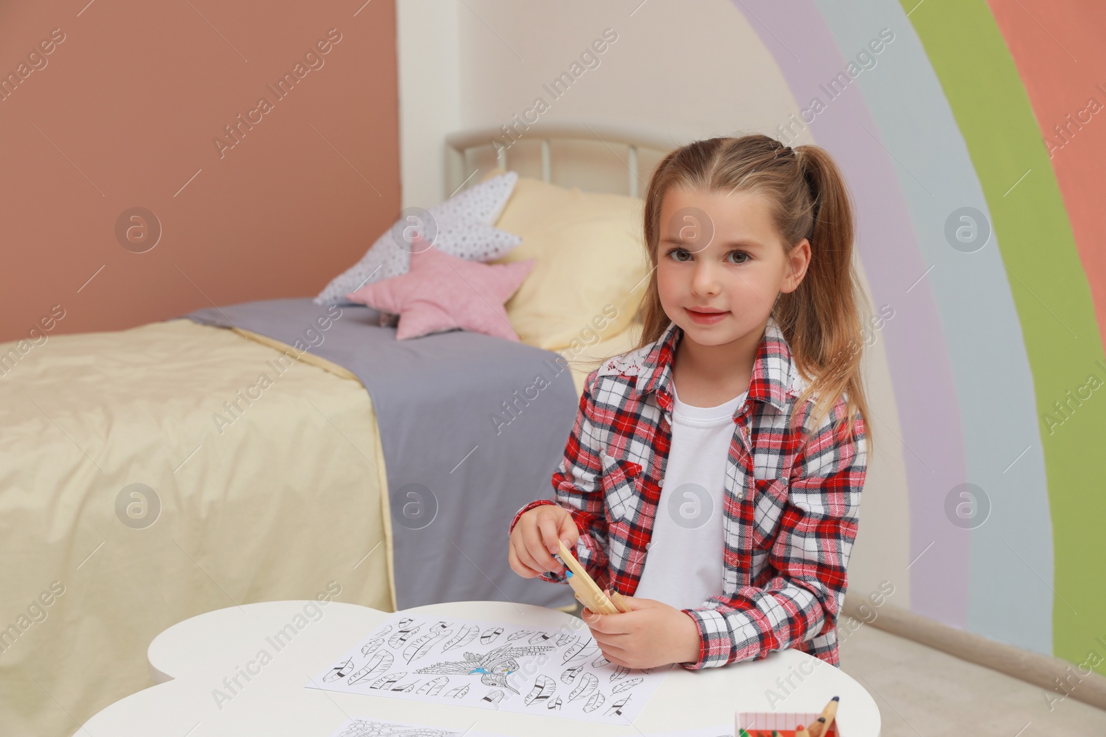 Photo of Little girl coloring antistress page at table indoors