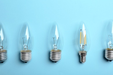 Vintage and modern lamp bulbs on light blue background, flat lay