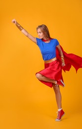 Photo of Confident woman wearing superhero costume on yellow background