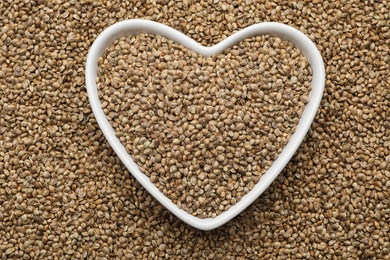 Photo of Heart shaped plate and organic hemp seeds, top view