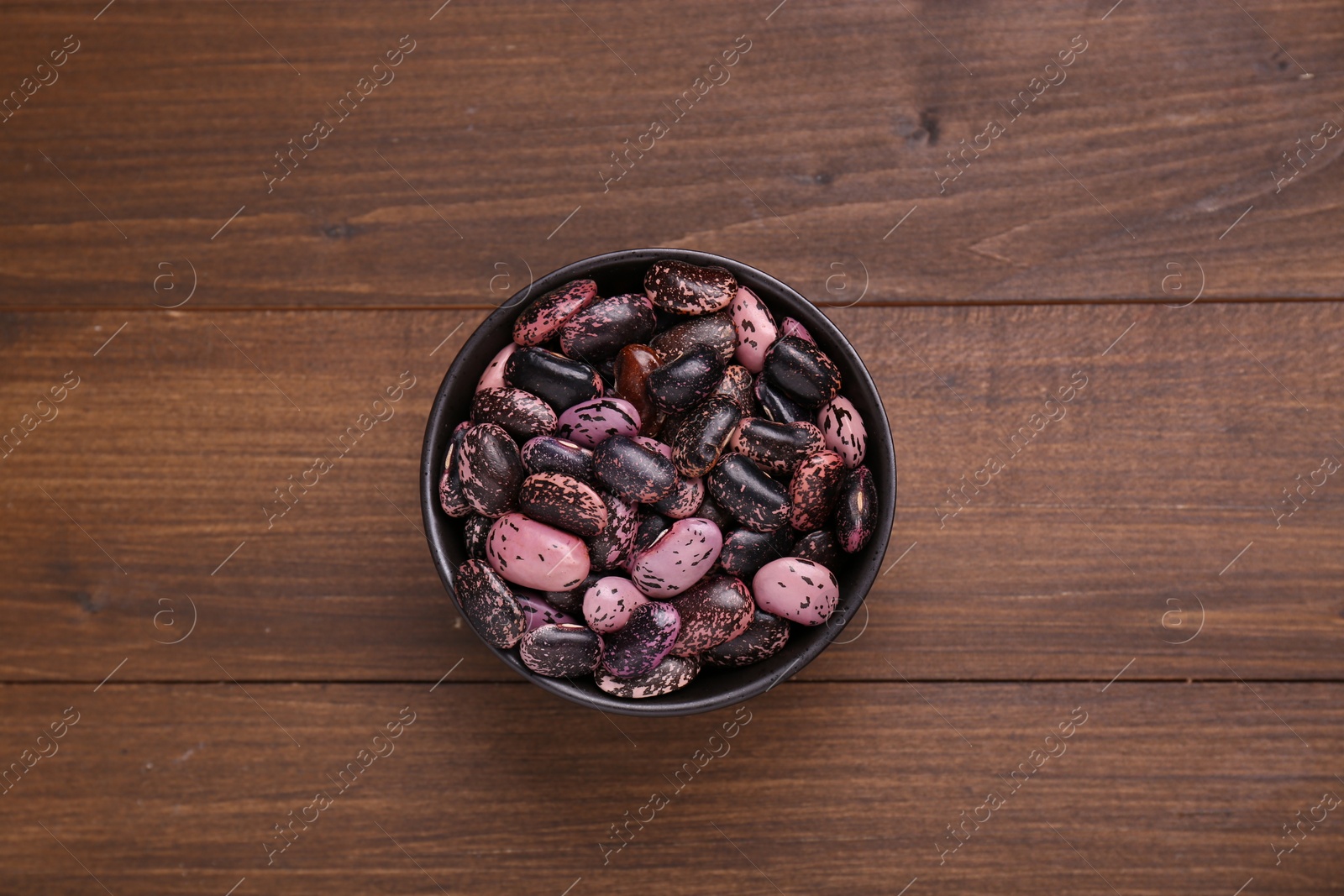 Photo of Bowl with dry kidney beans on wooden table, top view