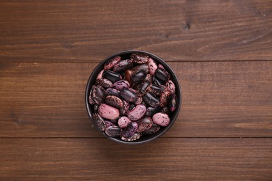 Photo of Bowl with dry kidney beans on wooden table, top view