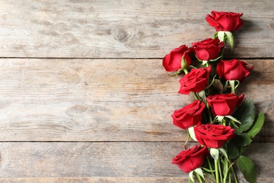 Beautiful red rose flowers on wooden background, top view