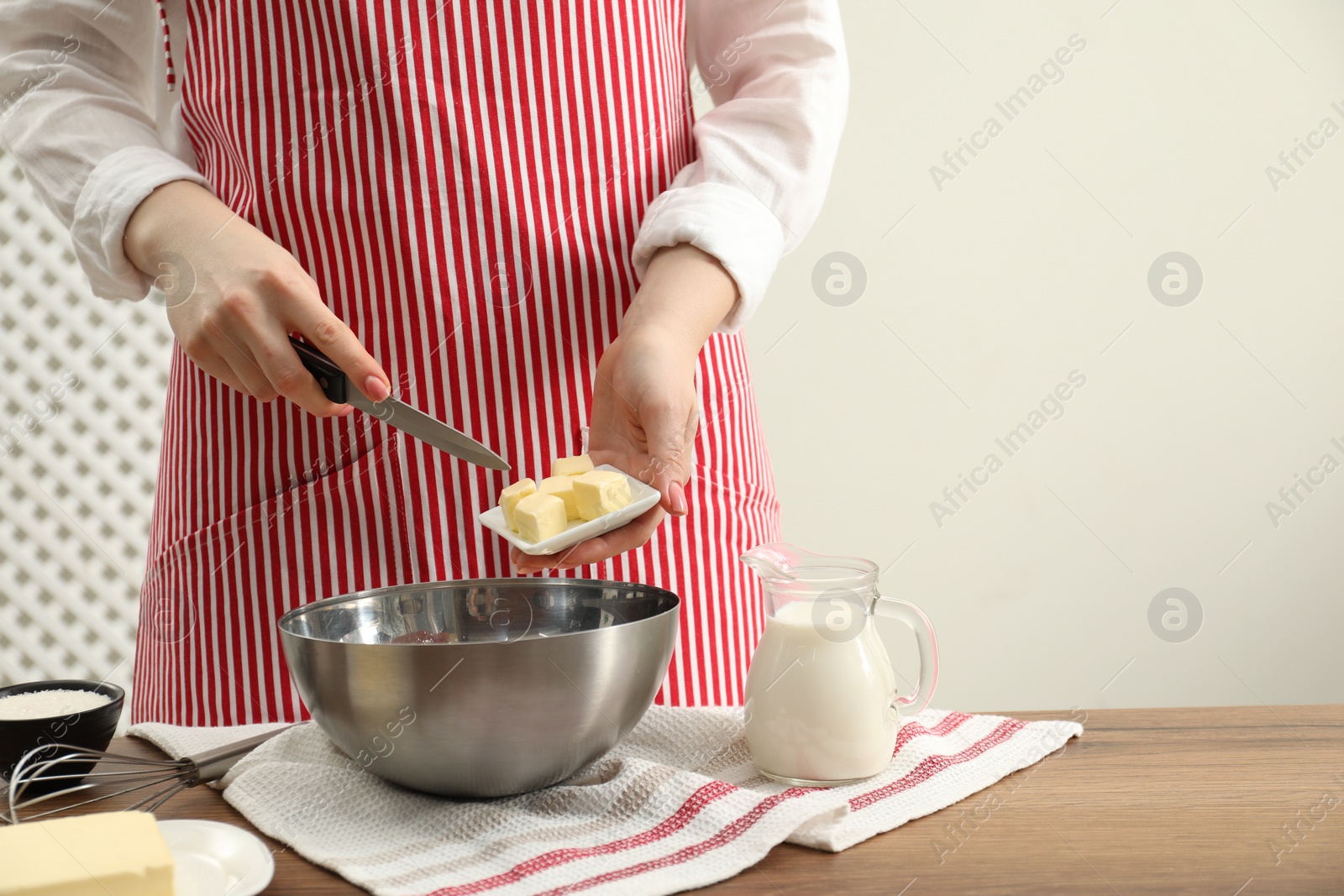 Photo of Woman adding fresh butter into bowl at wooden table, closeup