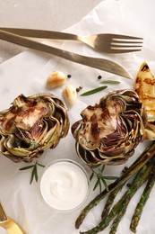 Photo of Tasty grilled artichoke served on table, top view