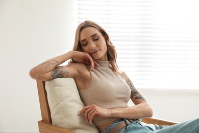 Photo of Beautiful woman with tattoos on arms resting at home