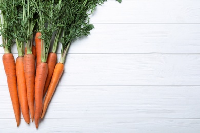 Ripe carrots on white wooden table, flat lay. Space for text