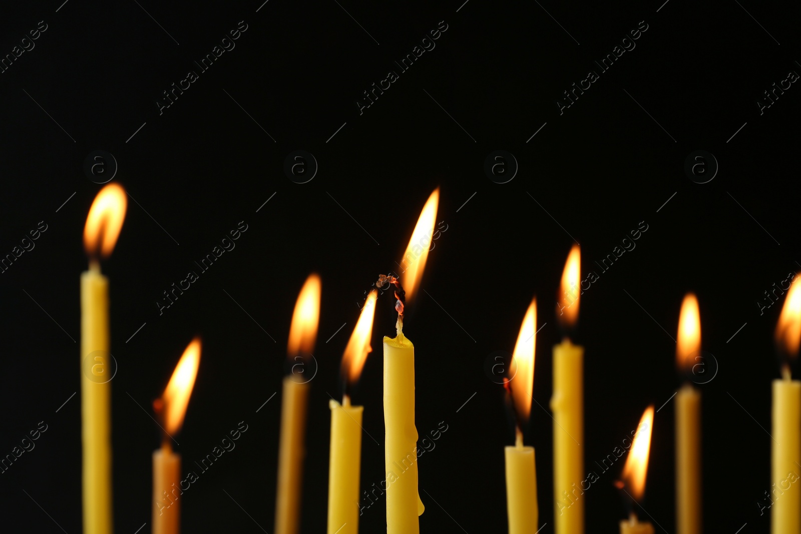 Photo of Burning candles on black background. Symbol of sorrow