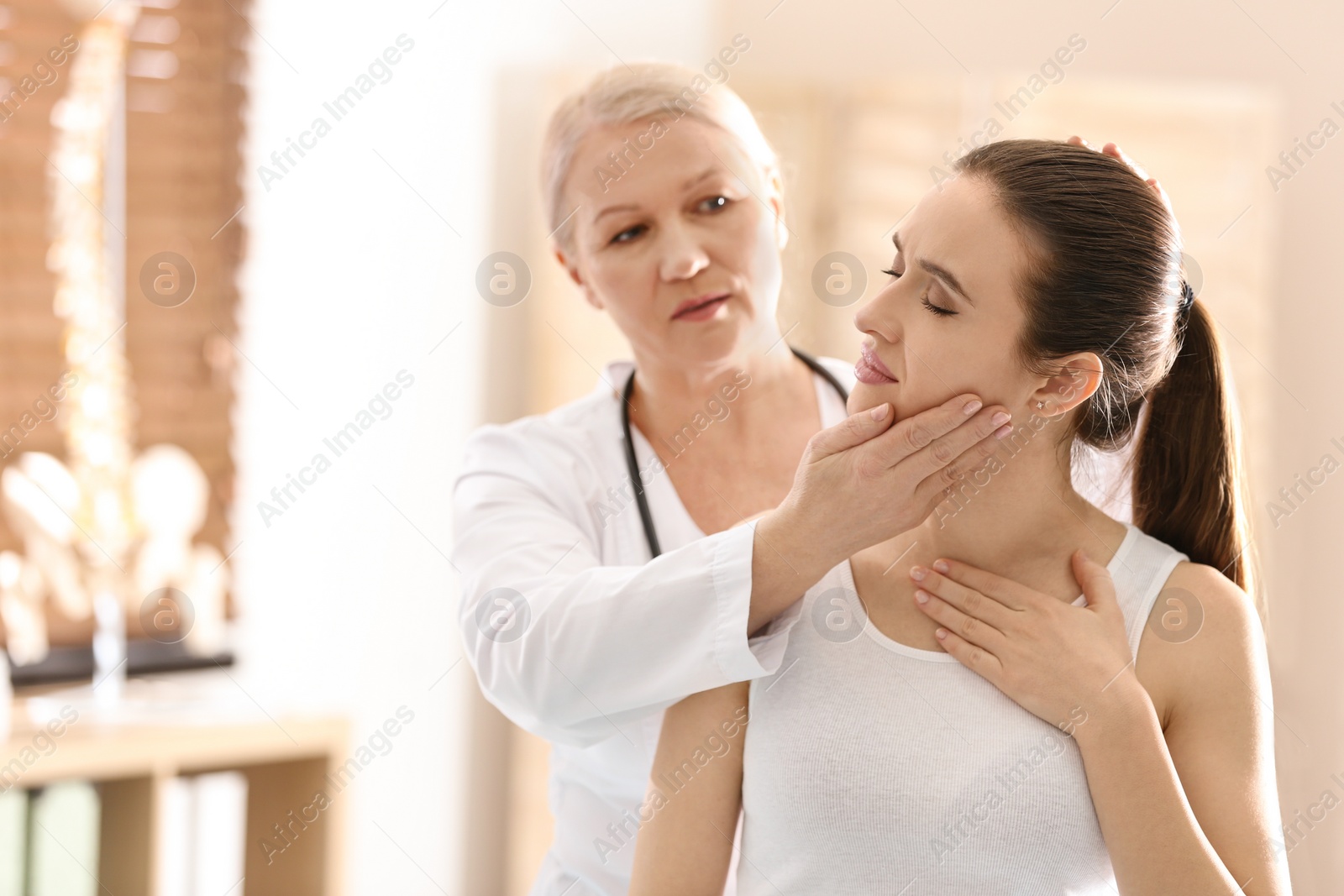 Photo of Female orthopedist examining patient's neck in clinic