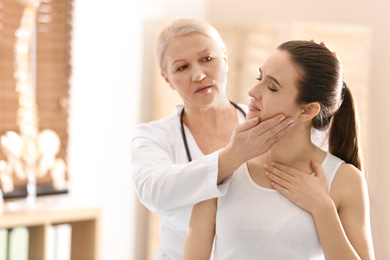 Female orthopedist examining patient's neck in clinic