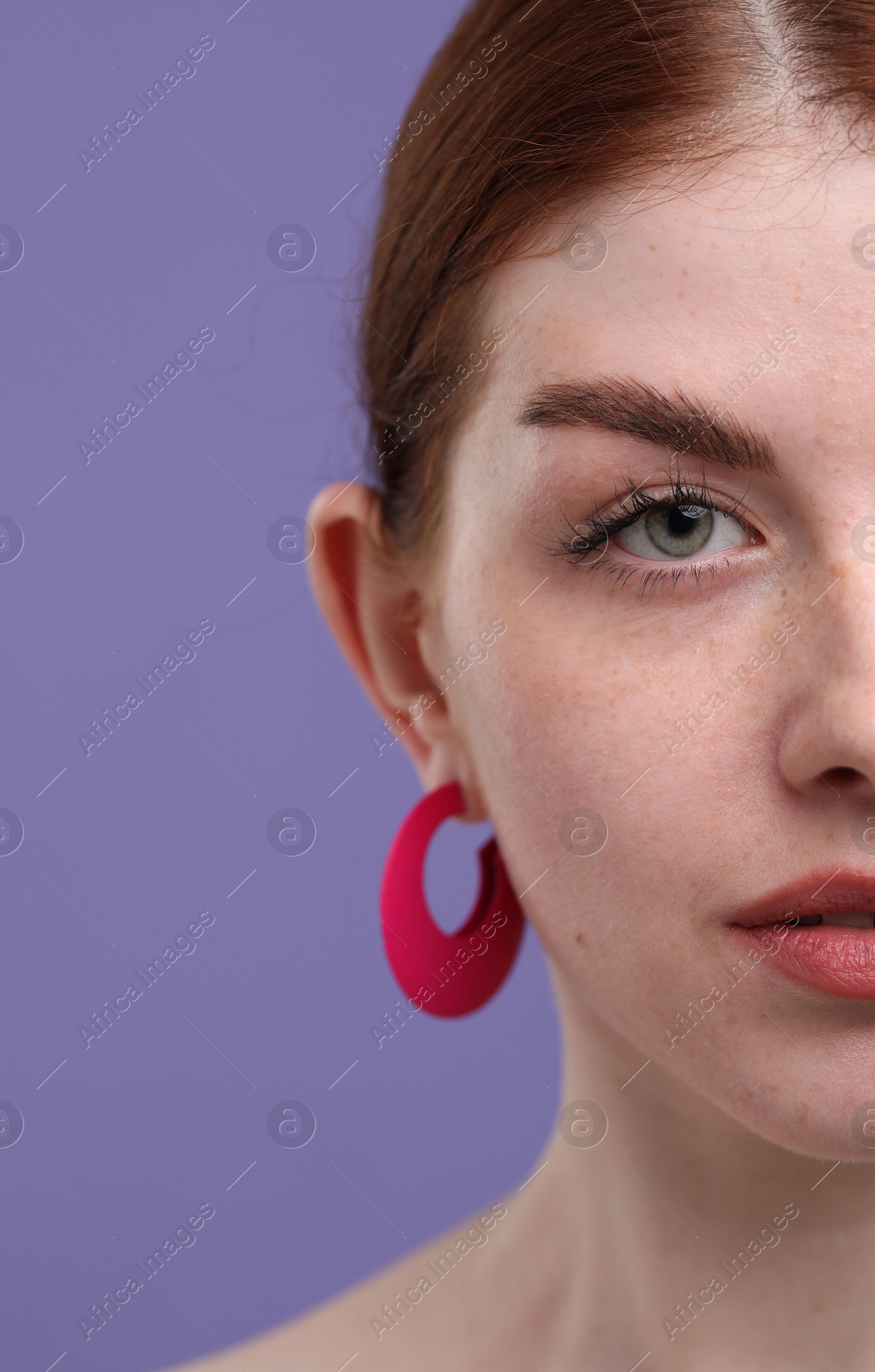 Photo of Beautiful woman with freckles on purple background, closeup