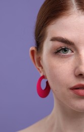 Beautiful woman with freckles on purple background, closeup