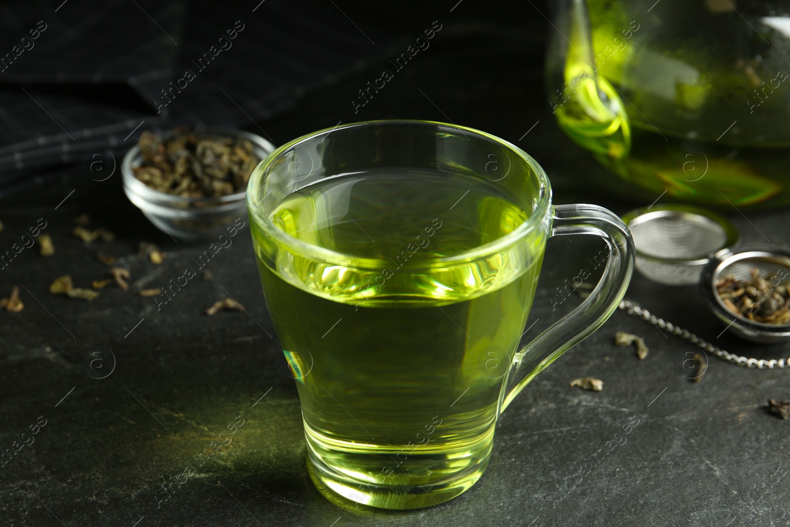 Photo of Cup of aromatic green tea on grey table