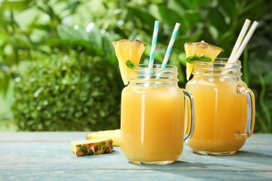 Photo of Composition with delicious pineapple juice on table against blurred background