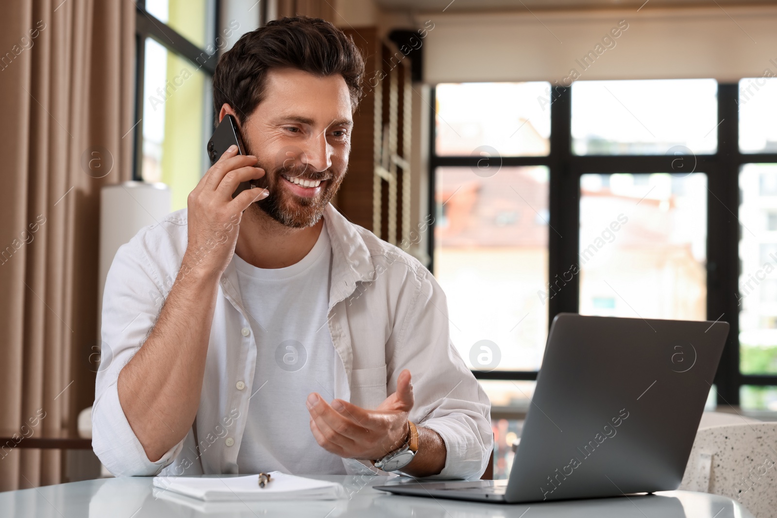 Photo of Handsome man talking on phone at table in cafe