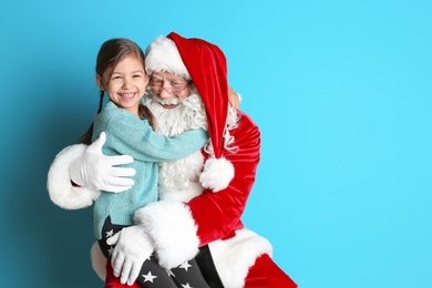 Photo of Little girl hugging authentic Santa Claus on color background