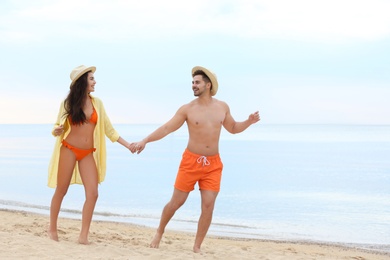 Happy young couple walking together on beach near sea