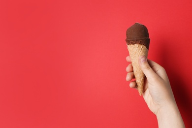 Photo of Woman holding ice cream in waffle cone against color background, space for text