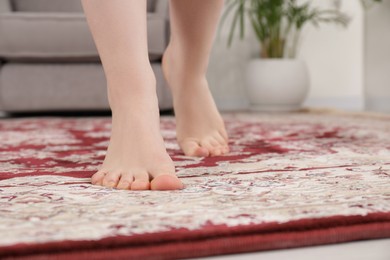 Photo of Woman standing on carpet with pattern at home, closeup. Space for text